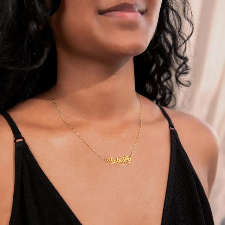 gold paw print pet name necklace on model's neck