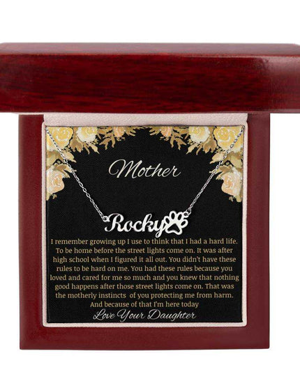 A polished stainless-steel pet name paw print necklace in a mahogany box.