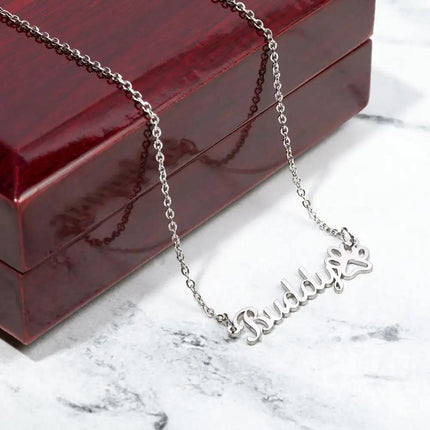 A polished stainless-steel pet name paw print necklace on a closed mahogany box