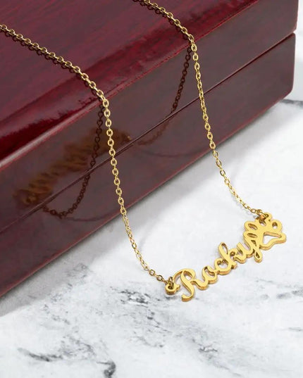 gold paw print pet name necklace on top of mahogany box