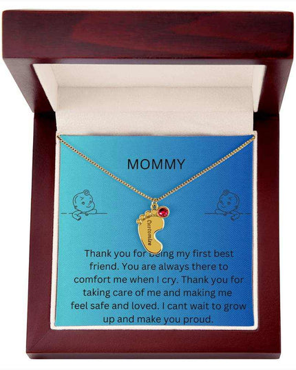 a yellow gold baby feet birthstone necklace in a mahogany box