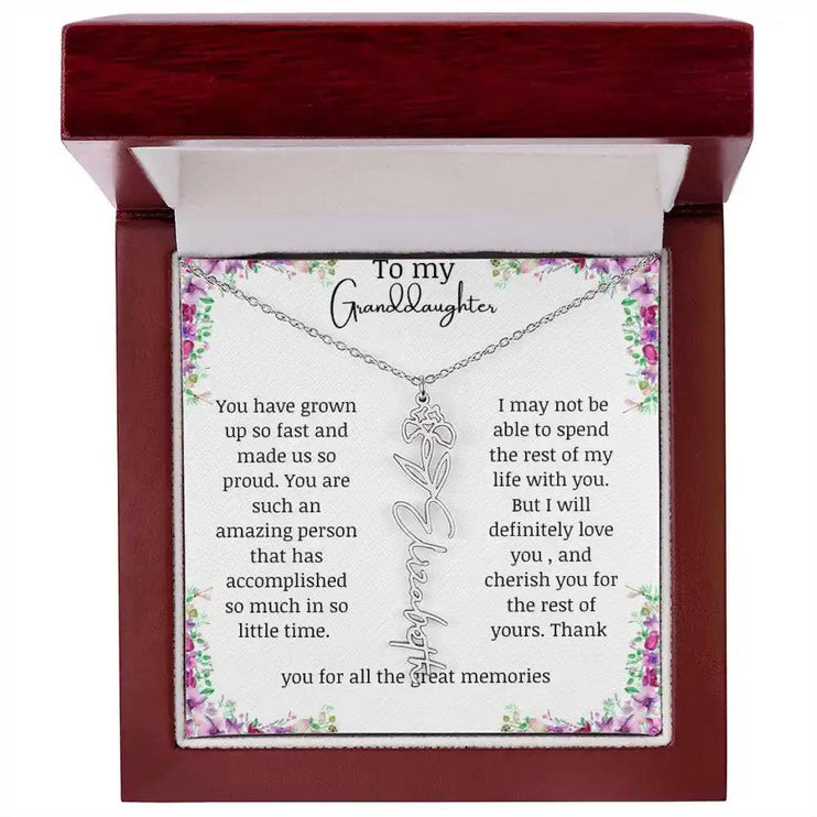 a polished stainless-steel February birth flower name necklace in a mahogany box.