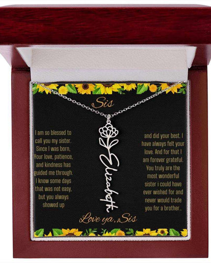 Birth Flower Name Necklace with a polished stainless-steel variant of a flower on a To Sis from Sis message card in a mahogany box up close