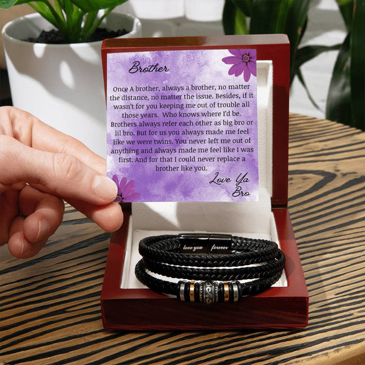 A men's love you forever bracelet in a mahogany box on a table.