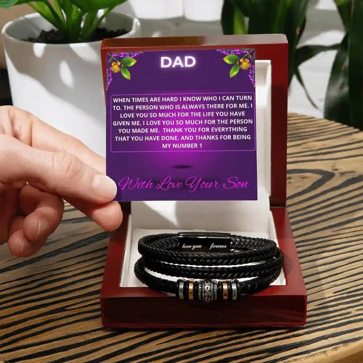 A men's love you forever bracelet in a mahogany box with a to dad greeting card on a table