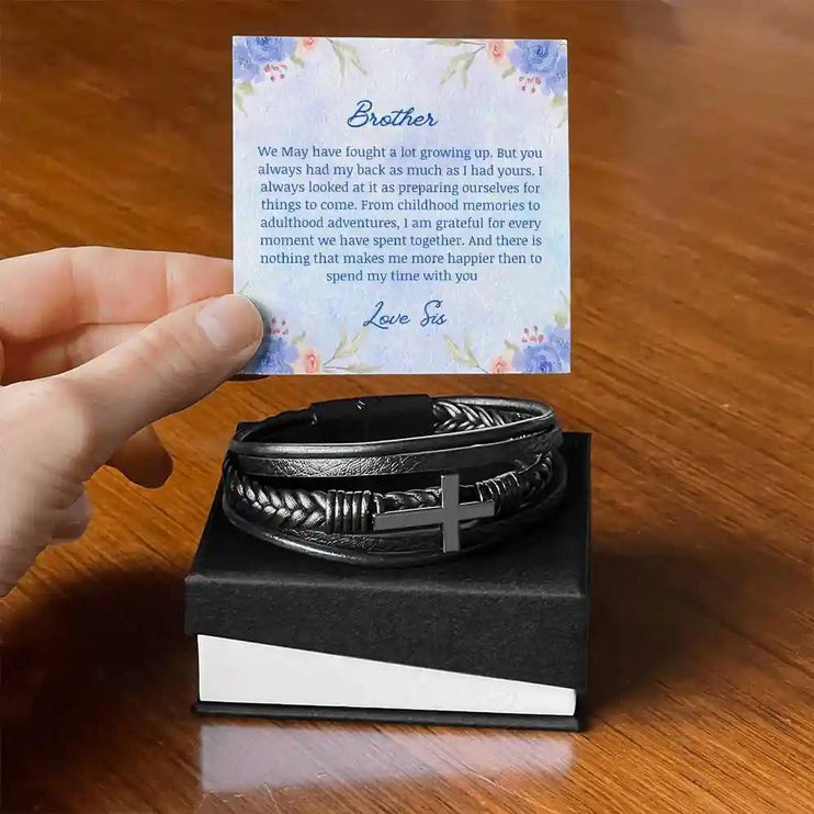 A men's cross leather bracelet in a two-tone box with a to brother card on a table.