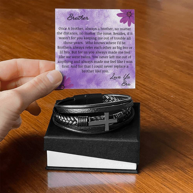 A men's cross leather bracelet in a two-tone box with to brother card on a table