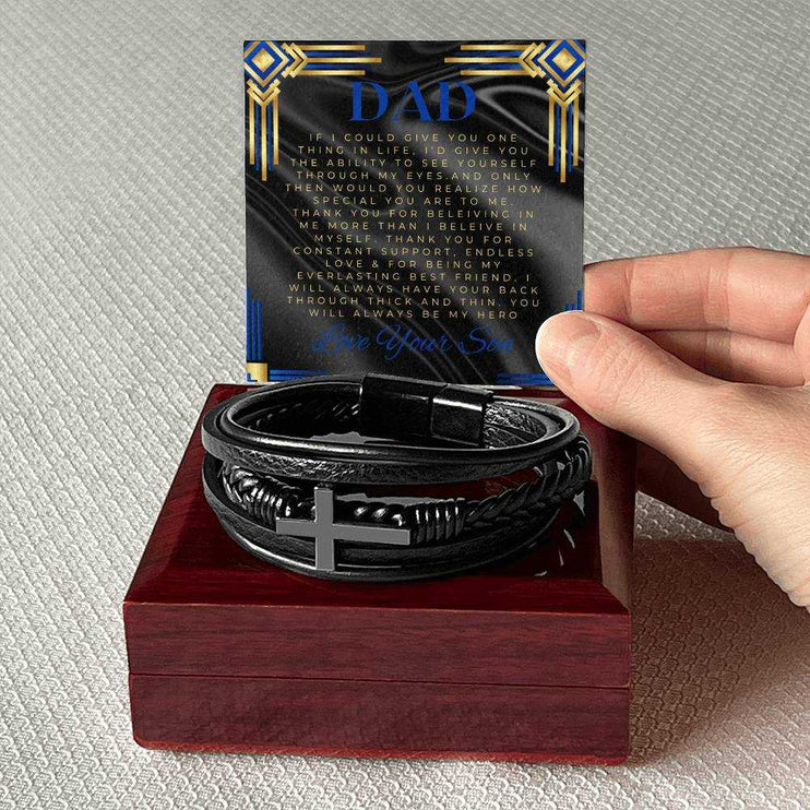 A men's cross leather bracelet on top of a mahogany box with a to dad greeting card 