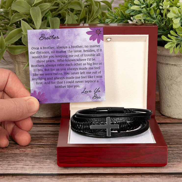 A men's cross leather bracelet in a mahogany box with a to brother card on a table