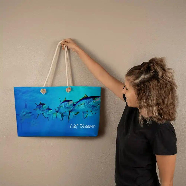 a weekend tote bag with model holding it up to wall with rope straps.