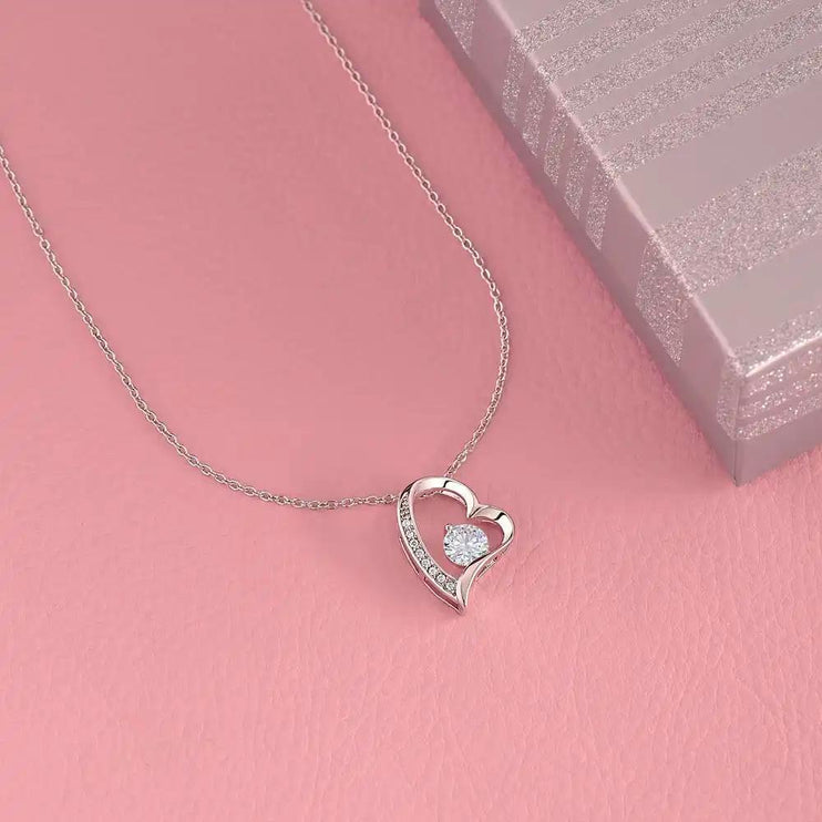 white gold forever love necklace in on a pink table