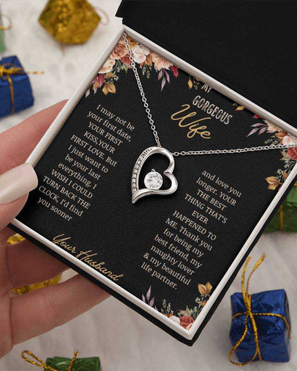 A white gold Forever Love Necklace on a to wife greeting card in a models hands close up.