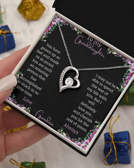Forever Love Necklace with a white gold charm on a for granddaughter from grandpa greeting card in a two-tone box in a models hand angled to the left