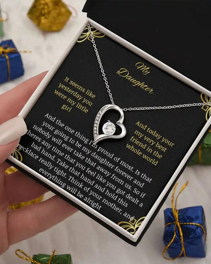 Forever Love Necklace with a white gold charm in a two-tone box with a to daughter from mom greeting card in a hand tilted left further away