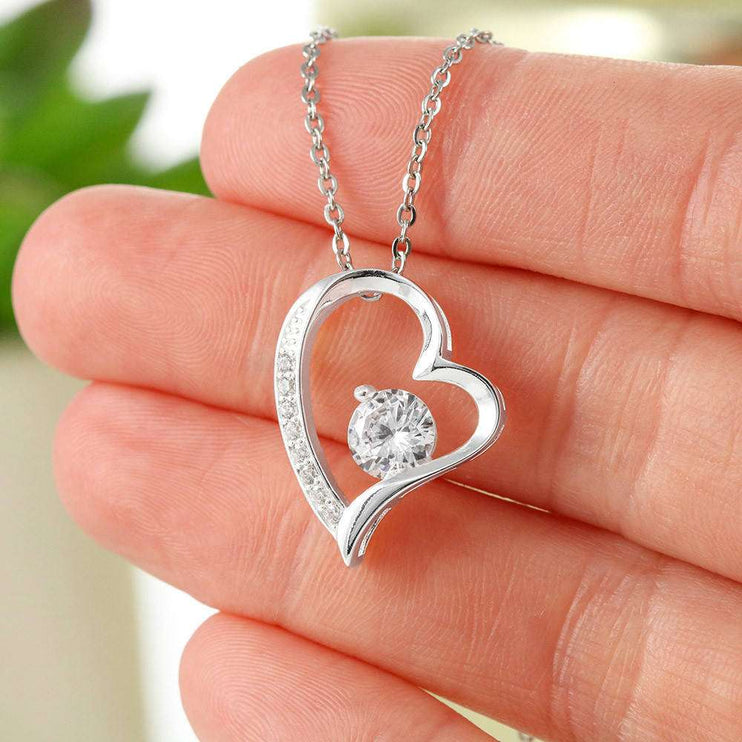 white gold forever love necklace in a models fingers