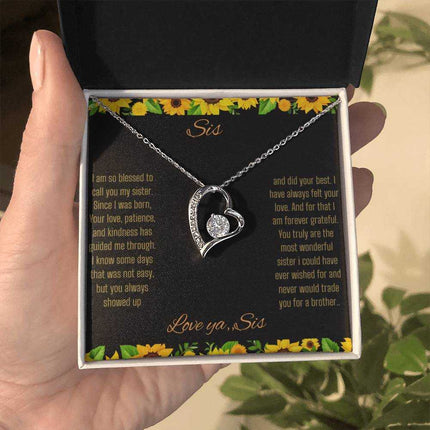 Forever Love Necklace with a white gold charm on a To Sis from Sis greeting card up close in a models hand in a two-tone box