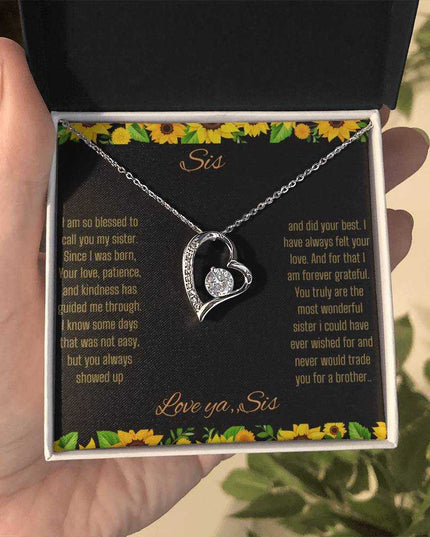 Forever Love Necklace with a white gold charm on a To Sis from Sis greeting card up close in a models hand in a two-tone box