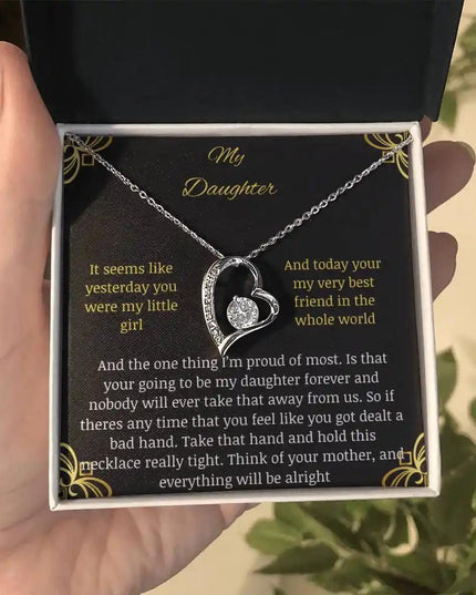 Forever Love Necklace with a white gold charm in a two-tone box with a greeting card to daughter from mom held in a hand further away