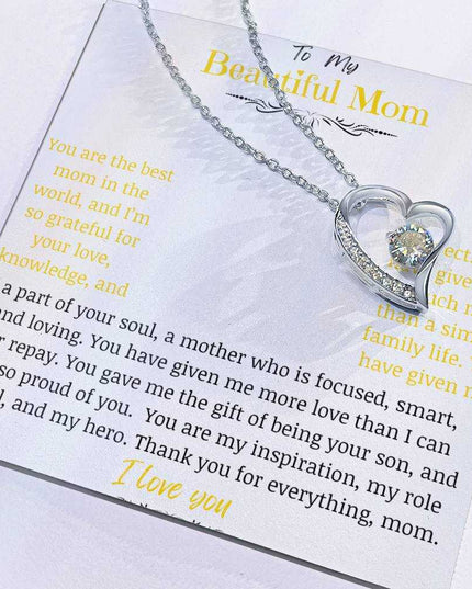 A white gold forever love necklace up close in a two-tone box with charm slid to side