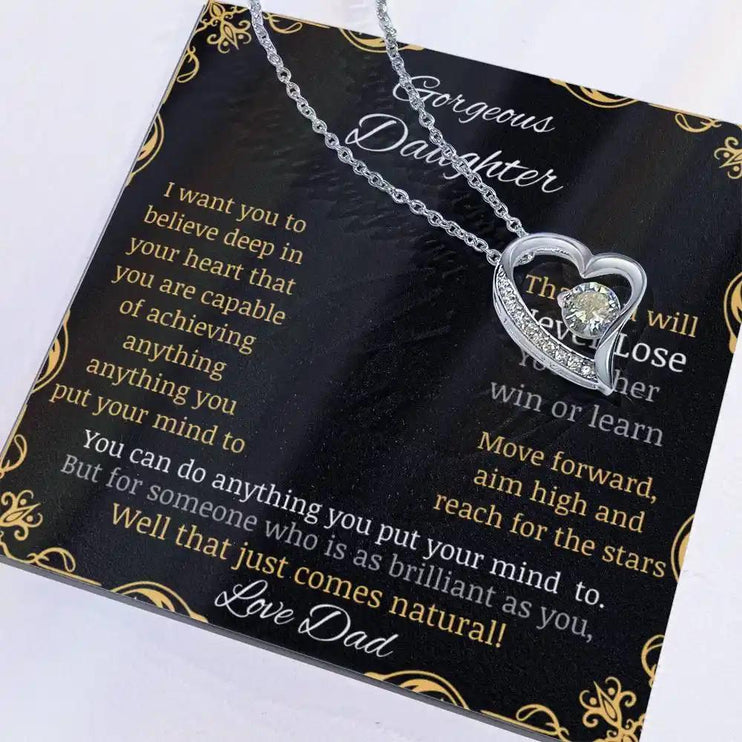Forever Love Necklace with a white gold pendant in a two-tone box with a to daughter from dad greeting card angled to the left close up with charm to the right