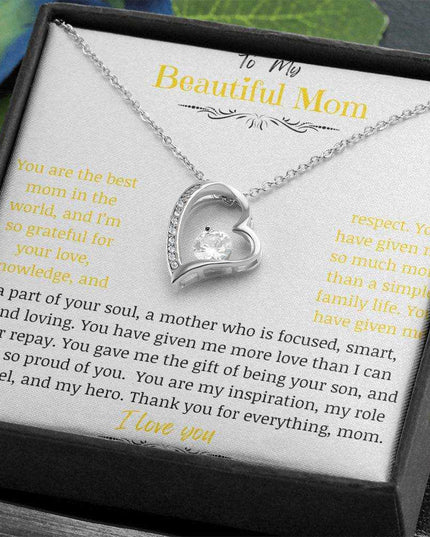 A white gold forever love necklace up close in a two-tone box in a hand angled to right
