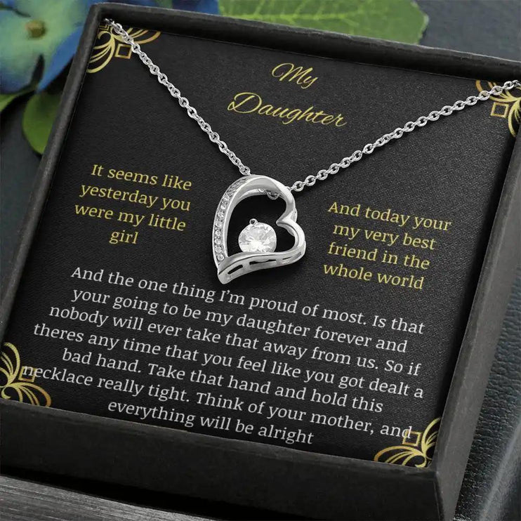 Forever Love Necklace with a white gold pendant in a two-tone box with a to daughter from mom greeting card angled away to the left with leaves around box