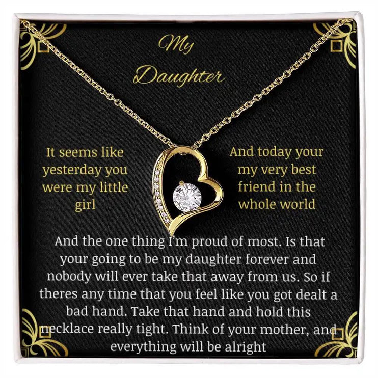 Forever Love Necklace with a yellow gold charm in a two-tone box with a to daughter from mom greeting card close up looking straight down