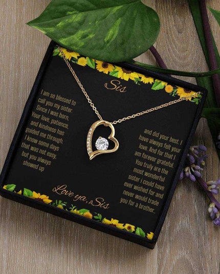 Forever Love Necklace with a white gold charm on a To Sis from Sis greeting card on a light brown table