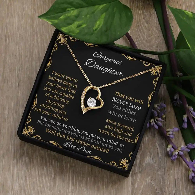 Forever Love Necklace with a yellow gold pendant in a two-tone box with a to daughter from dad greeting card angle further away on table angled left