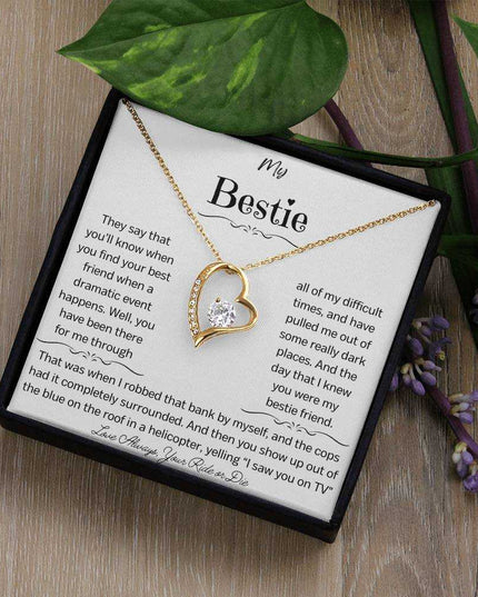 a yellow gold forever love necklace on a table