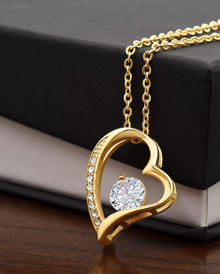 yellow gold forever love necklace on top of a soft box