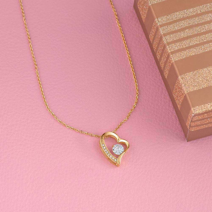 gold forever love necklace on a pink display table