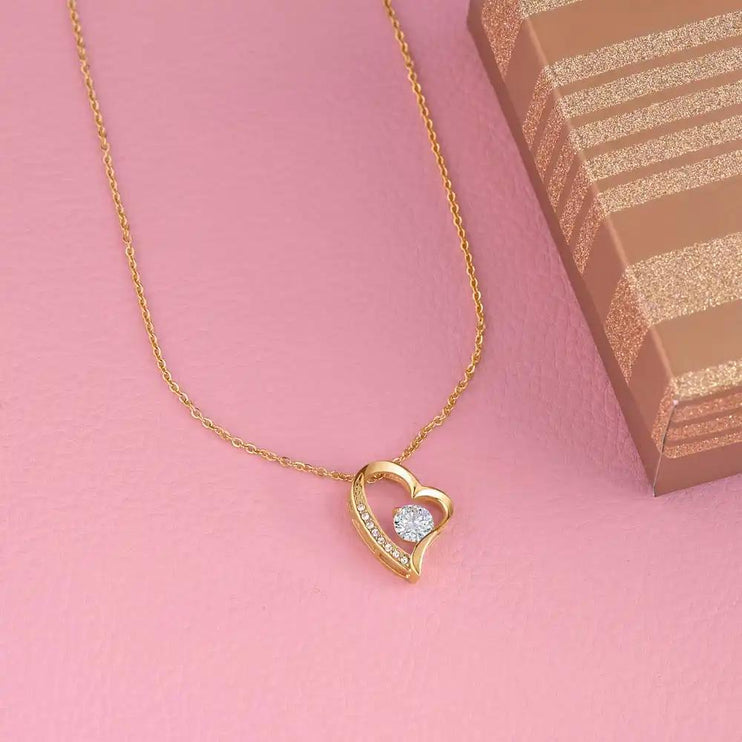 yellow gold forever love necklace on pink table