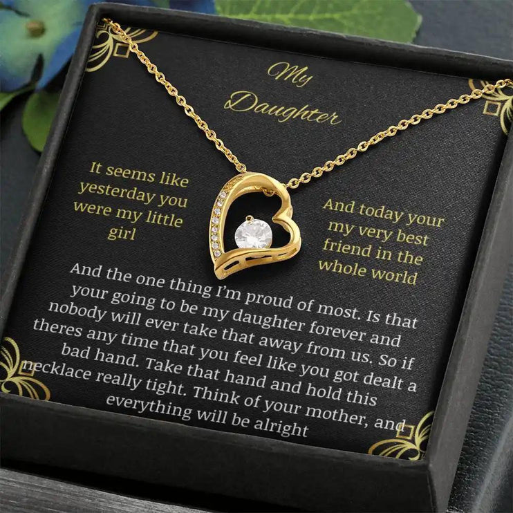 Forever Love Necklace with a yellow gold charm in a two-tone box with a to daughter from mom greeting card close up angled to left