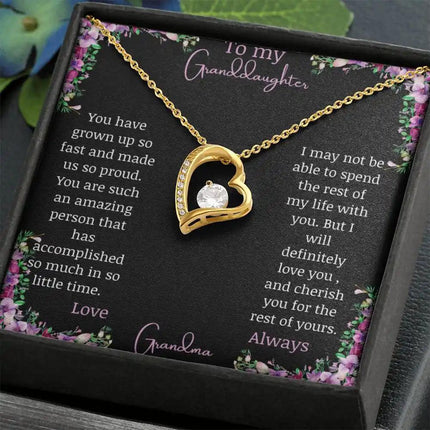 Forever Love Necklace with a yellow gold charm on a for granddaughter from grandpa greeting card in a two-tone box on a table angled left with a close up